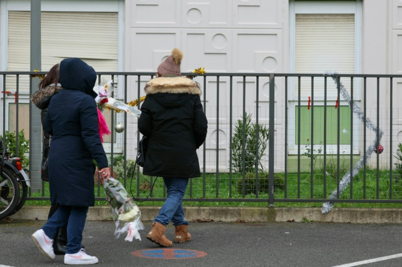 Des passants déposent des fleurs devant l'immeuble où les corps d'une femme et de ses quatre enfants ont été retrouvés, le 26 décembre 2023 à Meaux, en Seine-et-Marne © ALAIN JOCARD
