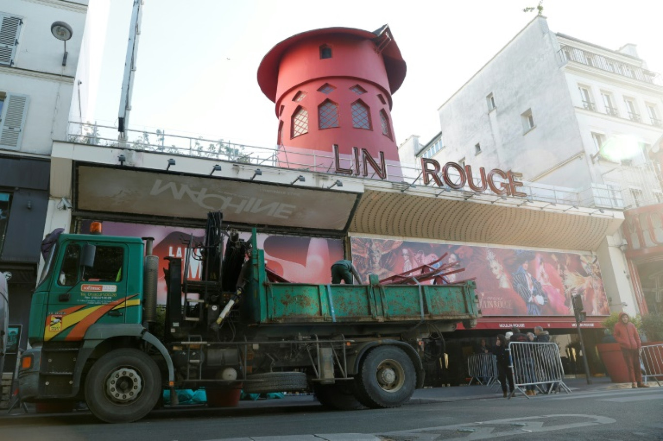 Des ouvriers sécurisent la zone devant le Moulin Rouge à Paris après que ses ailes et des lettres de la façade sont tombées dans la nuit sans faire de blessés, le 25 avril 2024 © Geoffroy VAN DER HASSELT