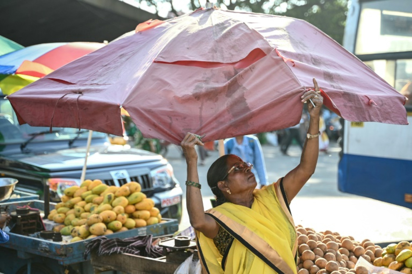 Une commerçante installe un parasol pour protéger son étal du soleil par une chaude journée d'été, le 29 avril 2024 à Bangalore, en Inde © Idrees MOHAMMED