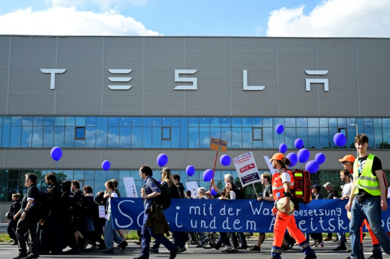 Des manifestants écologistes défilent devant l'usine de Tesla à Grünheide (près de Berlin, en Allemagne) pour protester contre un projet d'agrandissement, le 11 mai 2024 © JOHN MACDOUGALL