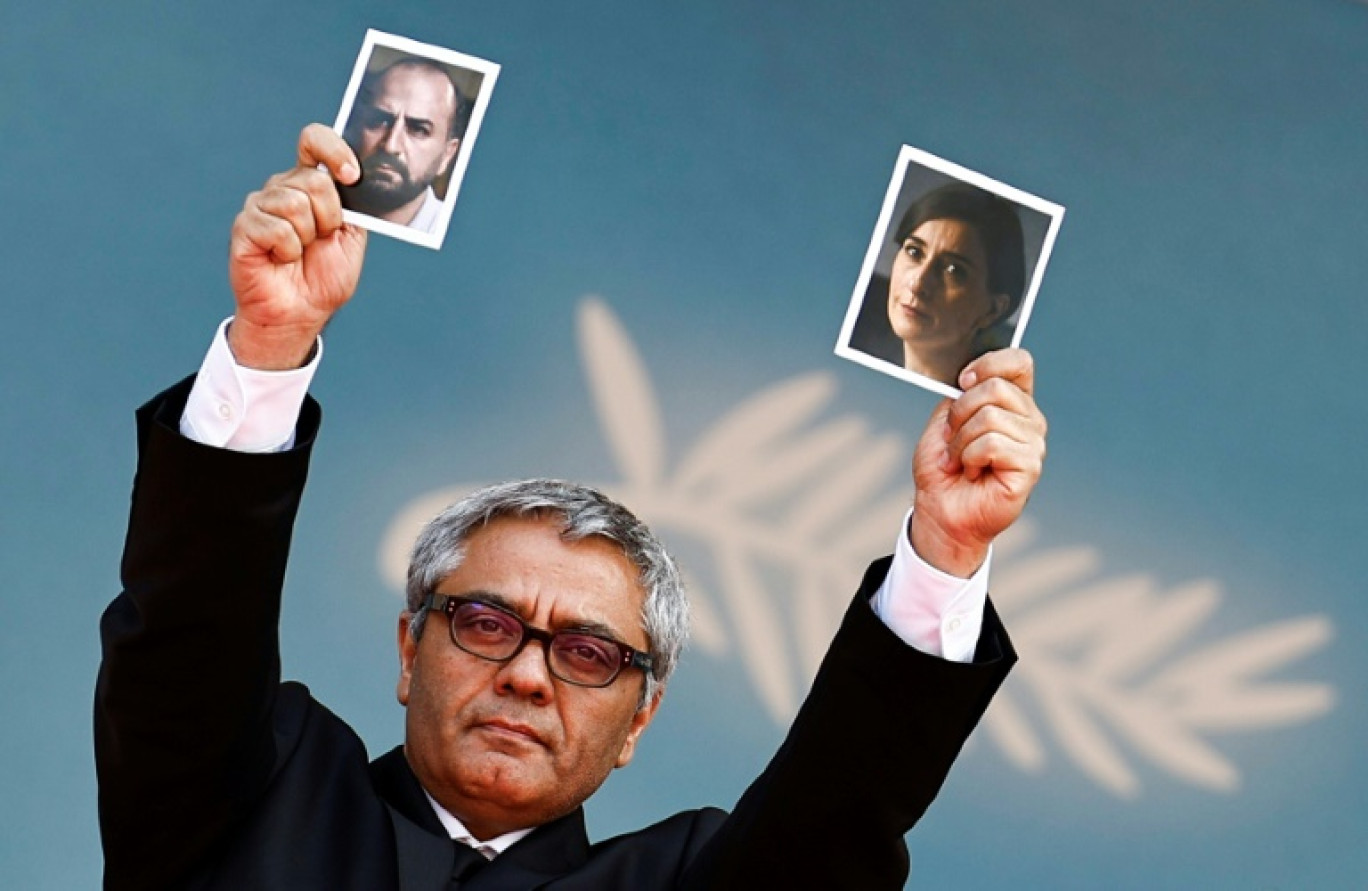 Iranian director Mohammad Rasoulof holds a portrait of Iranian actress Soheila Golestani (R) and Iranian actor Missagh Zareh (L) as he arrives for the screening of the film "The Seed of the Sacred Fig" at the 77th edition of the Cannes Film Festival in Cannes, southern France, on May 24, 2024. © Sameer Al-Doumy
