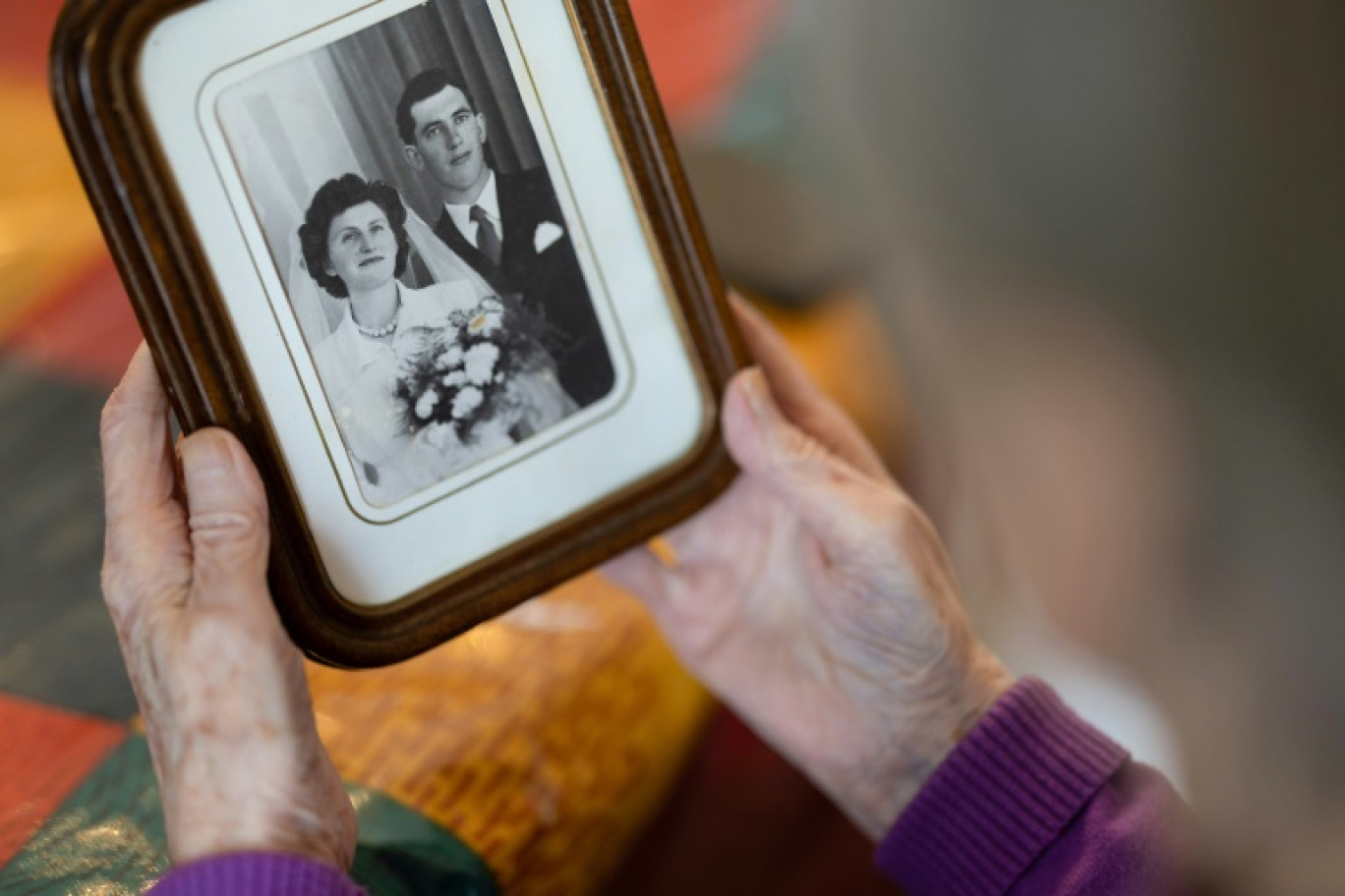Jeanne Tournellec regarde la photo de mariage de sa sœur Catherine Tournellec, violée par un soldat américain, et de son beau-frère Jean Salaun, chez elle à Locmaria-Plouzane, le 14 mars 2024 dans le Finistère © Fred TANNEAU