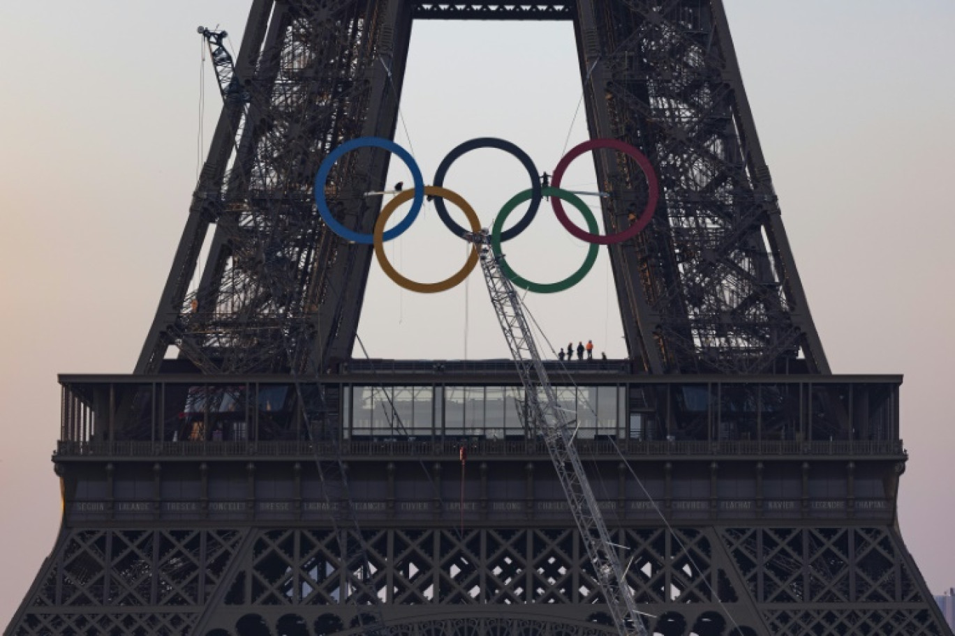 Des équipes finissent d'accrocher les anneaux olympiques à la tour Eiffel, le 7 juin 2024, à Paris © JOEL SAGET