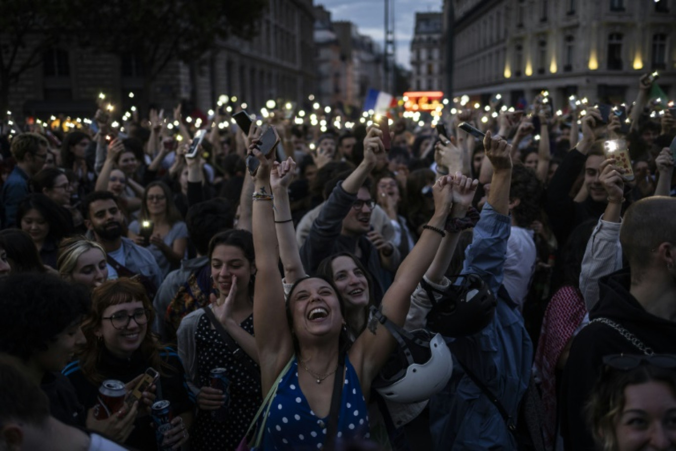 Une foule célèbre l'arrivée en tête surprise du Nouveau Front Populaire au second tour des élections législatives, le 7 juillet 2024 place de la République à Paris
People celebrate during an election night rally following the first results of the second round of France's legislative election at Republique Square in Paris on July 7, 2024. A broad left-wing coalition was leading a tight French legislative election, ahead of both President's centrists and the far right with no group winning an absolute majority, projections showed. © Olympia DE MAISMONT