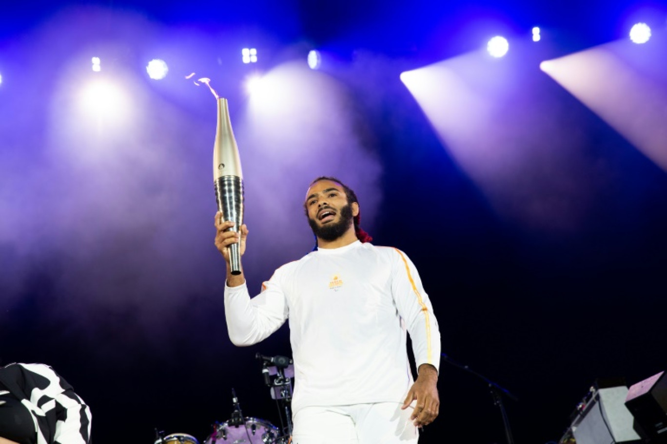 Le judoka français handisport Helios Latchoumanaya porte la flamme des Jeux paralympiques à Saint-Cloud, dans la banlieue de Paris le 25 août 2024 © Anna KURTH