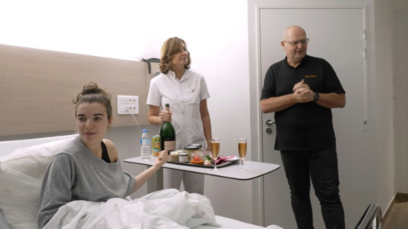 Paola Pontacq, 19 ans, étudiante sage-femme, atteinte d'un cancer du sein, dans son lit d'hôpital alors qu'on lui sert un repas préparé par le chef étoilé Pierre Reboul du restaurant Château de la Pioline, à l'Hôpital privé de Provence, à Aix-en-Provence, le 30 octobre 2024 © Viken KANTARCI