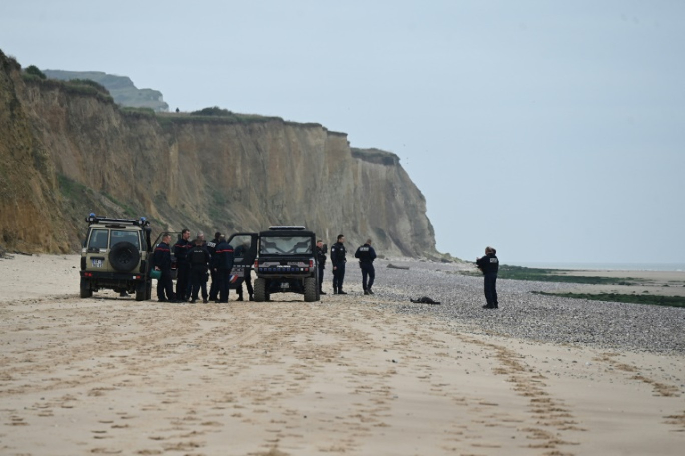Des policiers près d'un corps découvert sur la plage de Sangatte, près de Calais, d'où de nombreux migrants tentent la traversée de la Manche, le 2 novembre 2024 dans le Pas-de-Calais © Bernard BARRON
