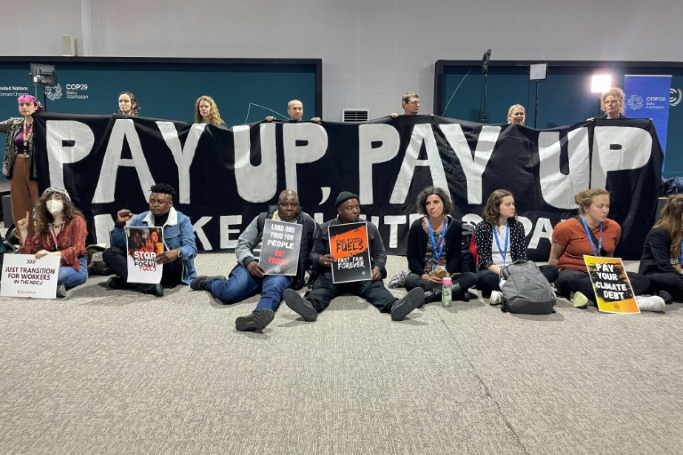 Plusieurs activistes mènent une action silencieuse afin de demander de l'argent aux pays riches pour la lutte contre le changement climatique, à la COP29, le 16 novembre 2024 à Bakou. © Laurent THOMET