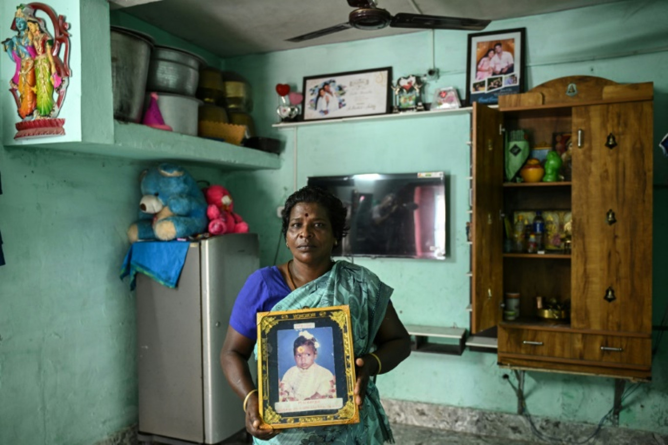 M Lakshmi, victime du tsunami de 2004, montre un portrait de sa fille Yashoda, morte dans la catastrophe, lors d'une interview avec l'AFP dans une colonie résidentielle construite pour les victimes du tsunami à Nagapattinam, le 7 novembre 2024 dans l'État du Tamil Nadu, en Inde © R. Satish BABU