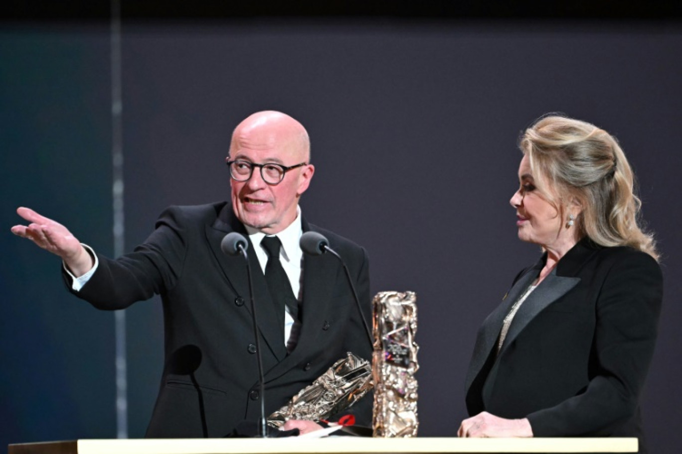 Le réalisateur Jacques Audiard (g) après avoir reçu le prix du meilleur long métrage pour le film "Emilia Perez", et l'actrice Catherine Deneuve (d) lors de la 50e édition de la cérémonie des César du cinéma à l'Olympia, à Paris, le 28 février 2025 © Bertrand GUAY