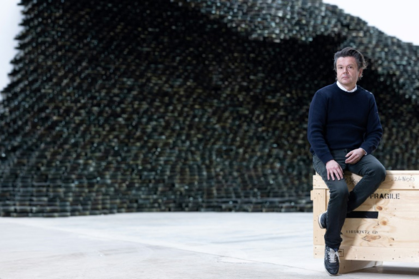 L'artiste français Jean-Michel Othoniel devant l'une de ses œuvres composées de 10 000 briques de verre noir en forme de vague, intitulée "Big Wave", dans son atelier de Montreuil, près de Paris, le 27 février 2025 © JOEL SAGET