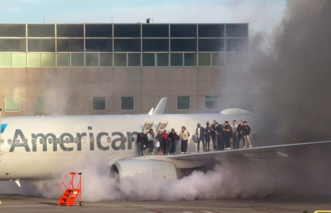 Des passagers attendent l'arrivée des secours sur une aile d'un avion d'American Airlines en feu, à Denver dans le Colorado le 13 mars 2025 © Branden Williams