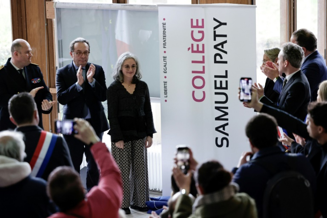 Le président du Département des Yvelines Pierre Bedier (2e g) et la sœur de Samuel Paty, Gaëlle Paty (3e g) lors de la cérémonie au cours de laquelle le collège du Bois d'Aulne prend officiellement le nom du professeur, à Conflans-Sainte-Honorine, le 14 mars 2025 près de Paris © STEPHANE DE SAKUTIN