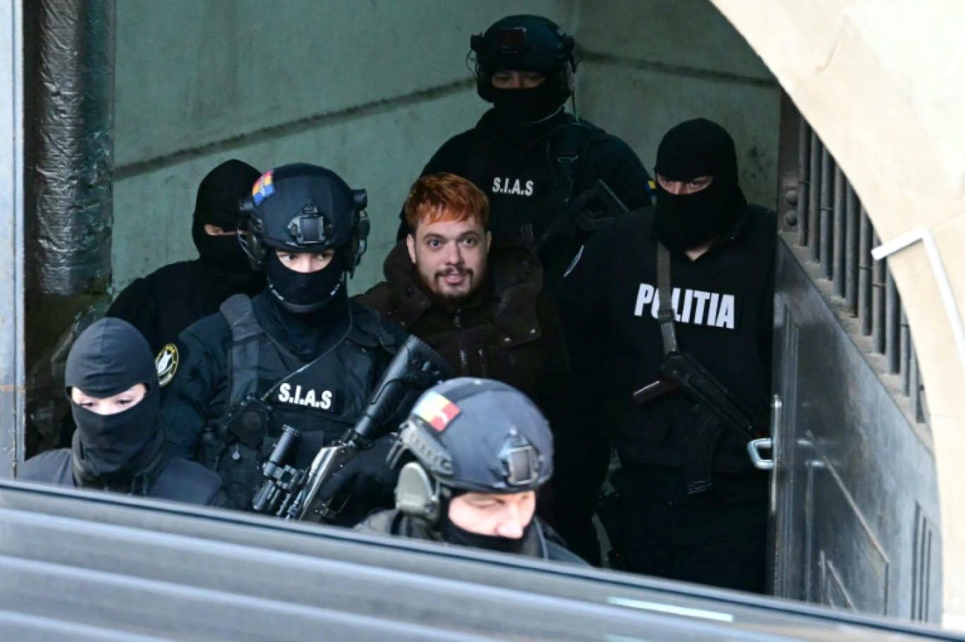 Mohamed Amra (C) escorté par des policiers le 23 février 2025 à Bucarest © Daniel MIHAILESCU
