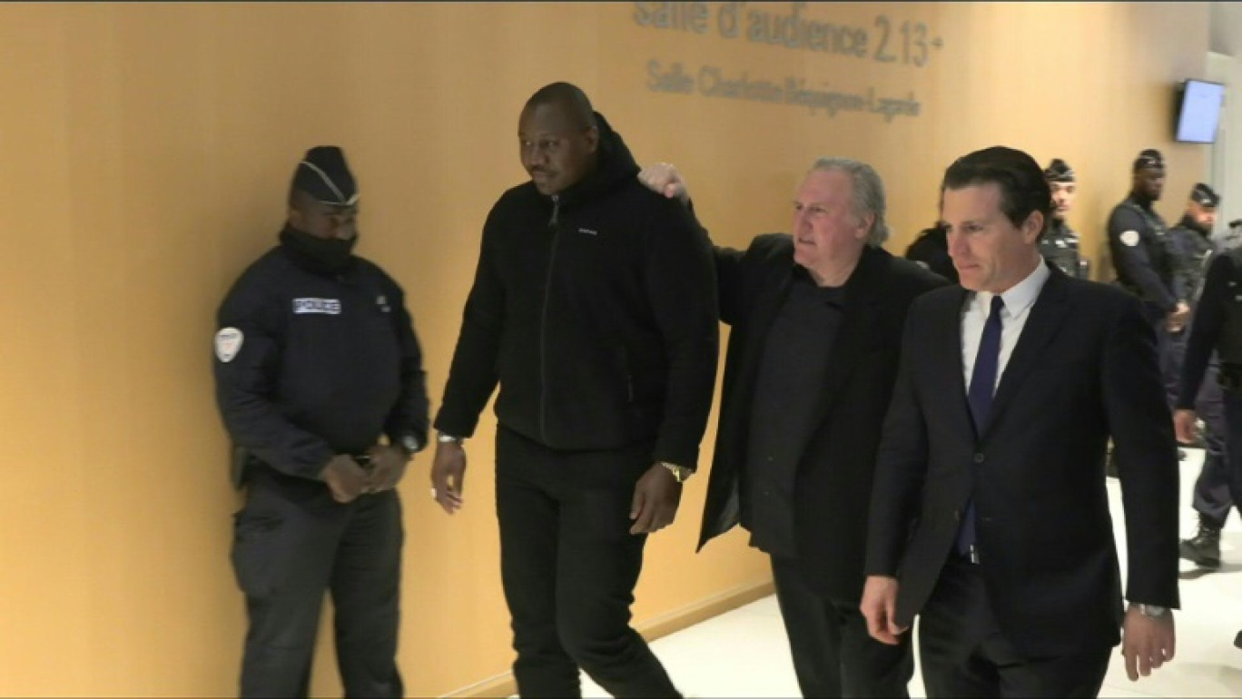 Gérard Depardieu (c) et son avocat Jérémie Assous (d) quittent la salle d'audience pendant une pause au tribunal correctionnel de Paris, le 25 mars 2025 © Dimitar DILKOFF
