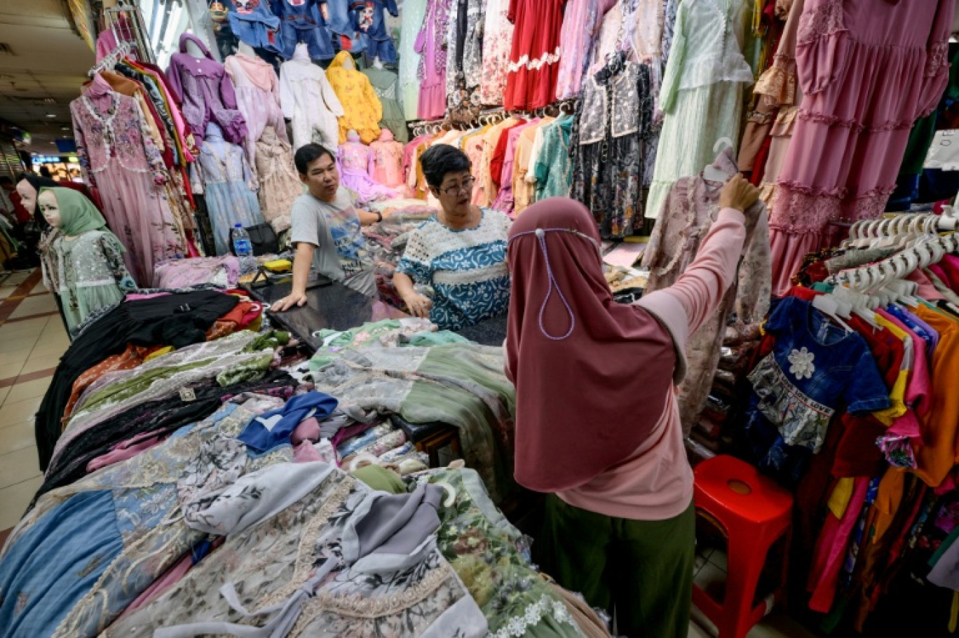 Une vendeuse aide une cliente à choisir des vêtements au marché de textile Tanah Abang, le 6 mars 2025 à Jakarta, en Indonésie © BAY ISMOYO