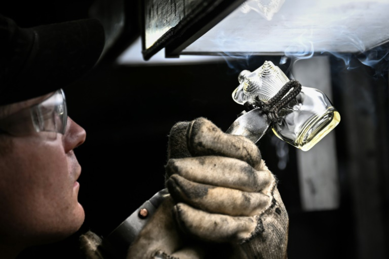A la verrerie Pochet du Courval en Seine-Maritime, un salarié en train d'examiner un flacon de parfum en cours de fabrication, le 28 mars 2025 © LOU BENOIST