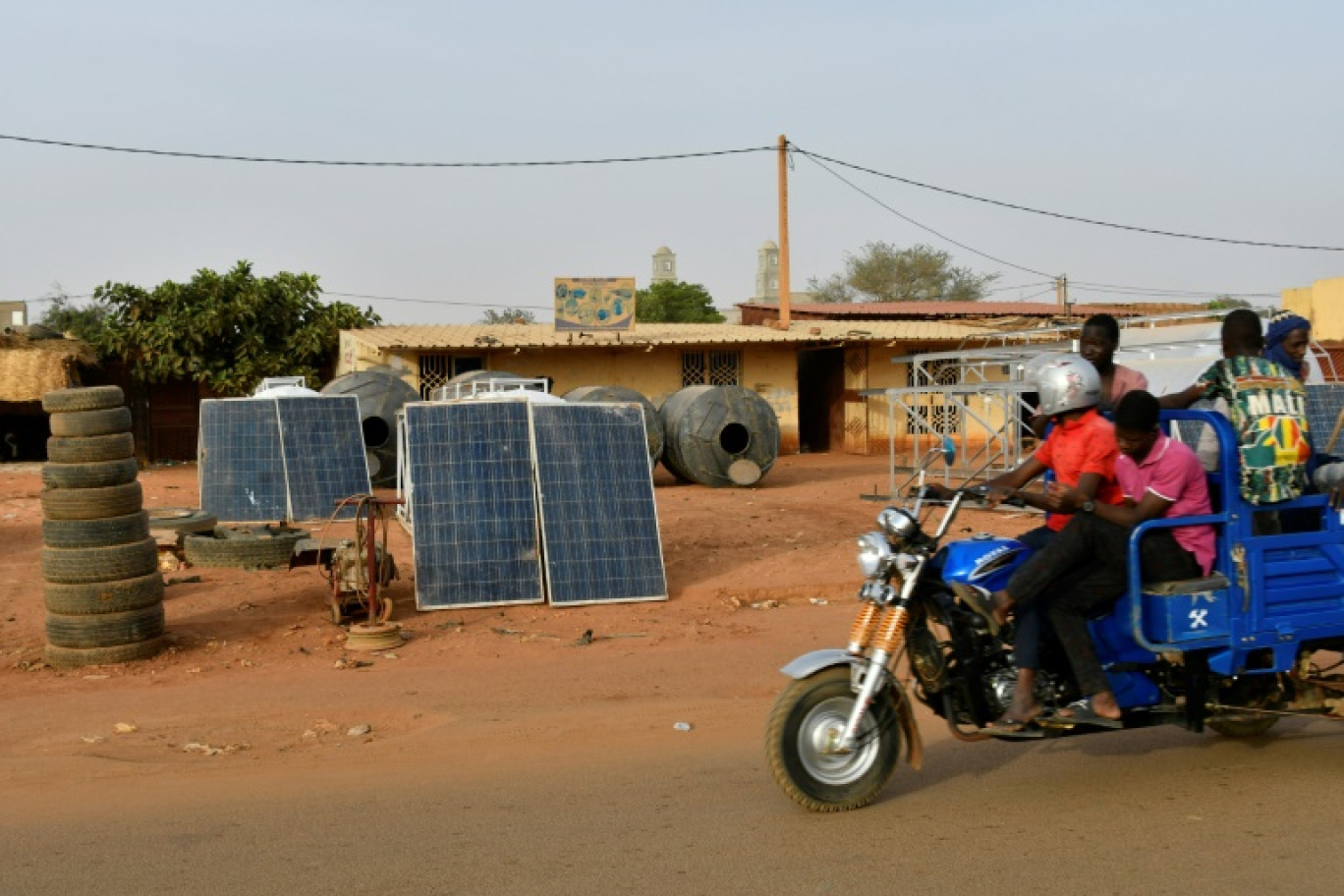 Une moto-taxi passe devant des panneaux solaires en vente dans une rue de Niamey, le 3 avril 2025 © BOUREIMA HAMA