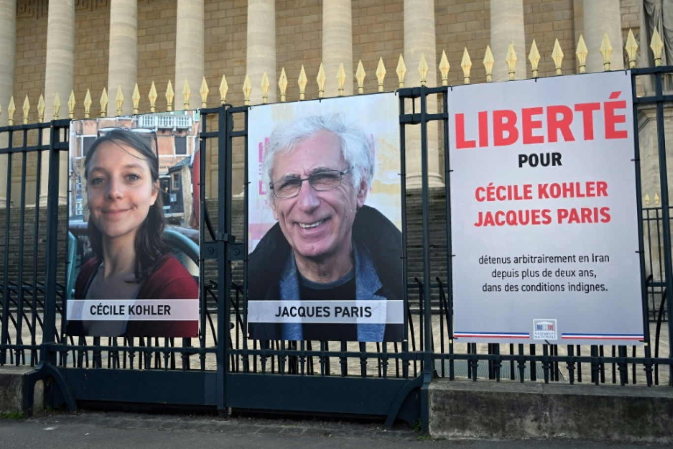 Les portraits de Cécile Kohler et de Jacques Paris, emprisonnés en Iran, accrochés aux grilles de l'Assemblée nationale à Paris, le 25 mars 2025 © Bertrand GUAY