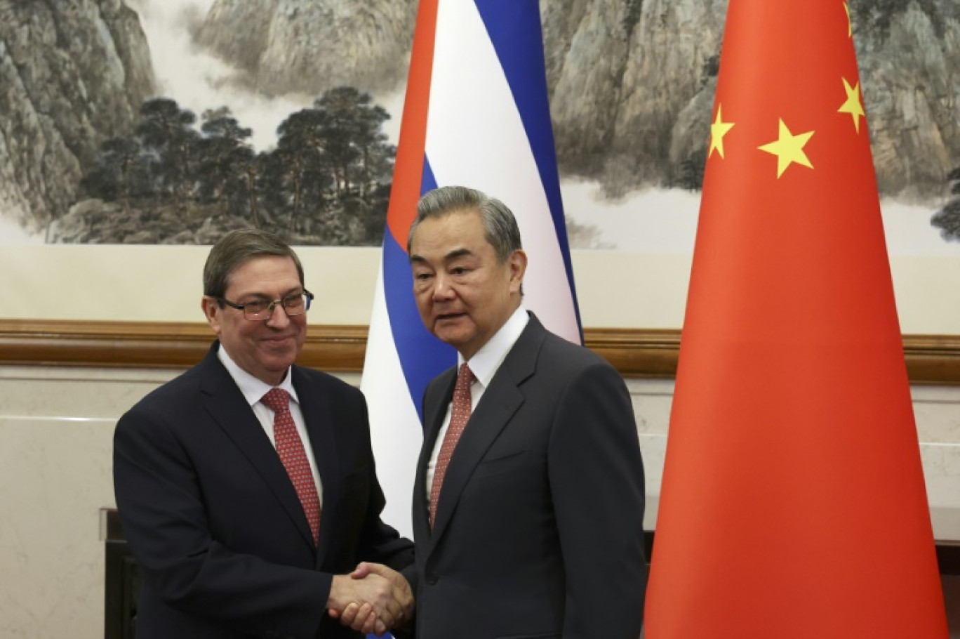 Le ministre chinois des Affaires étrangères Wang Yi (d) et le ministre cubain des Affaires étrangères Bruno Rodriguez Parrilla se serrent la main avant leur rencontre à la maison d'hôtes d'Etat Diaoyutai à Pékin, le 12 mai 2025 © FLORENCE LO