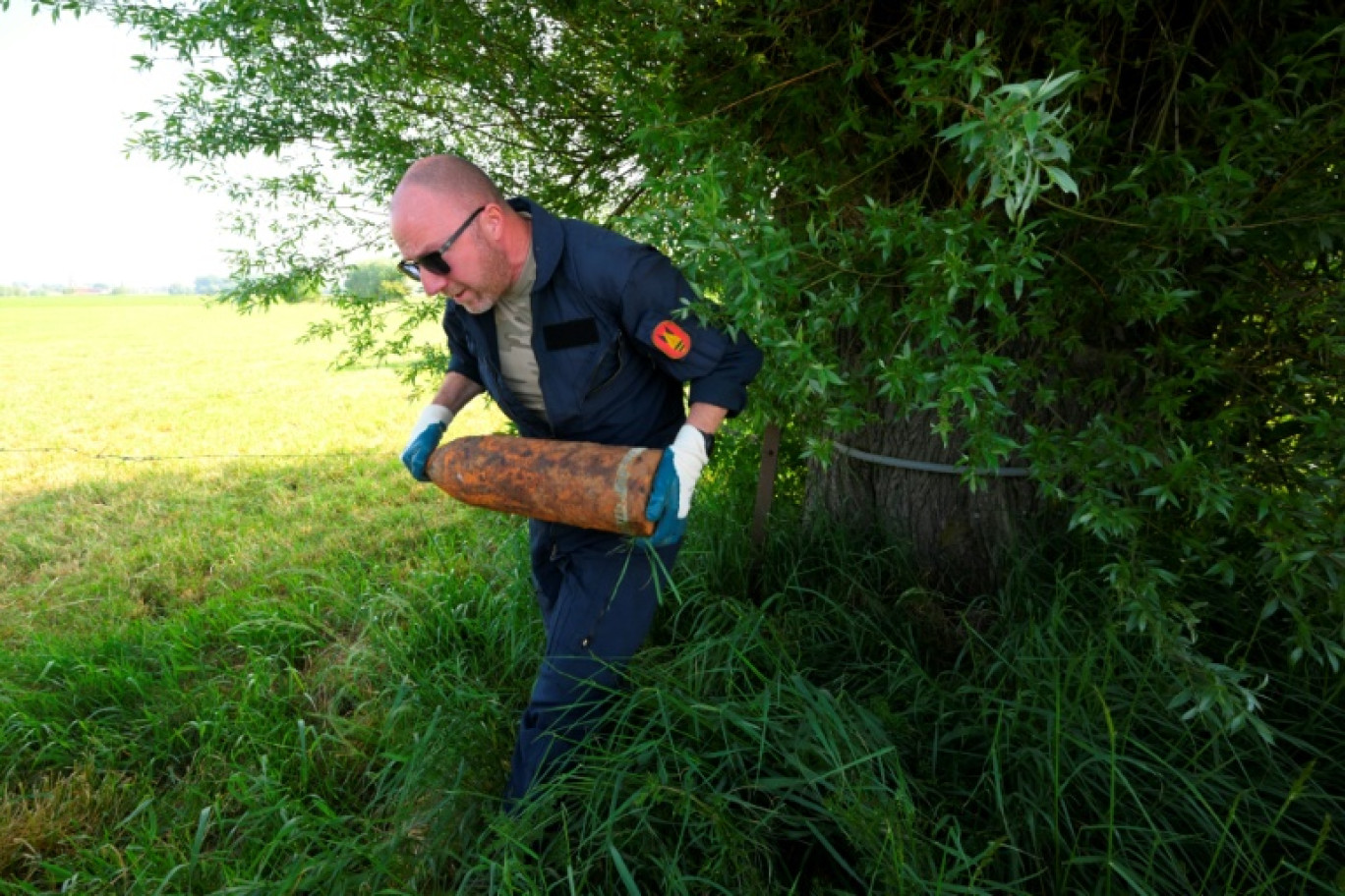 Un membre de l'équipe de déminage de la DOVO ramasse de vieux obus de la Première Guerre mondiale trouvés dans la campagne du nord-ouest de la Belgique, près d'Ypres, le 19 mai 2025 © Nicolas TUCAT