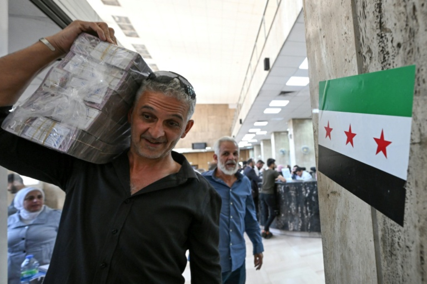 Un homme quitte la banque centrale de Damas avec des livres syriennes, le 21 mai 2025 © LOUAI BESHARA