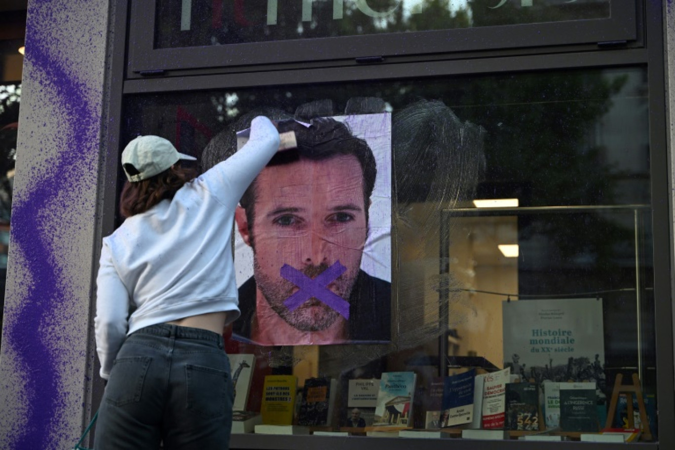 Une militante féministe colle une affiche dénonçant la publication d'un livre de Nicolas Bedos, condamné en octobre pour agressions sexuelles, le 23 mai 2025 à Paris © Leo VIGNAL