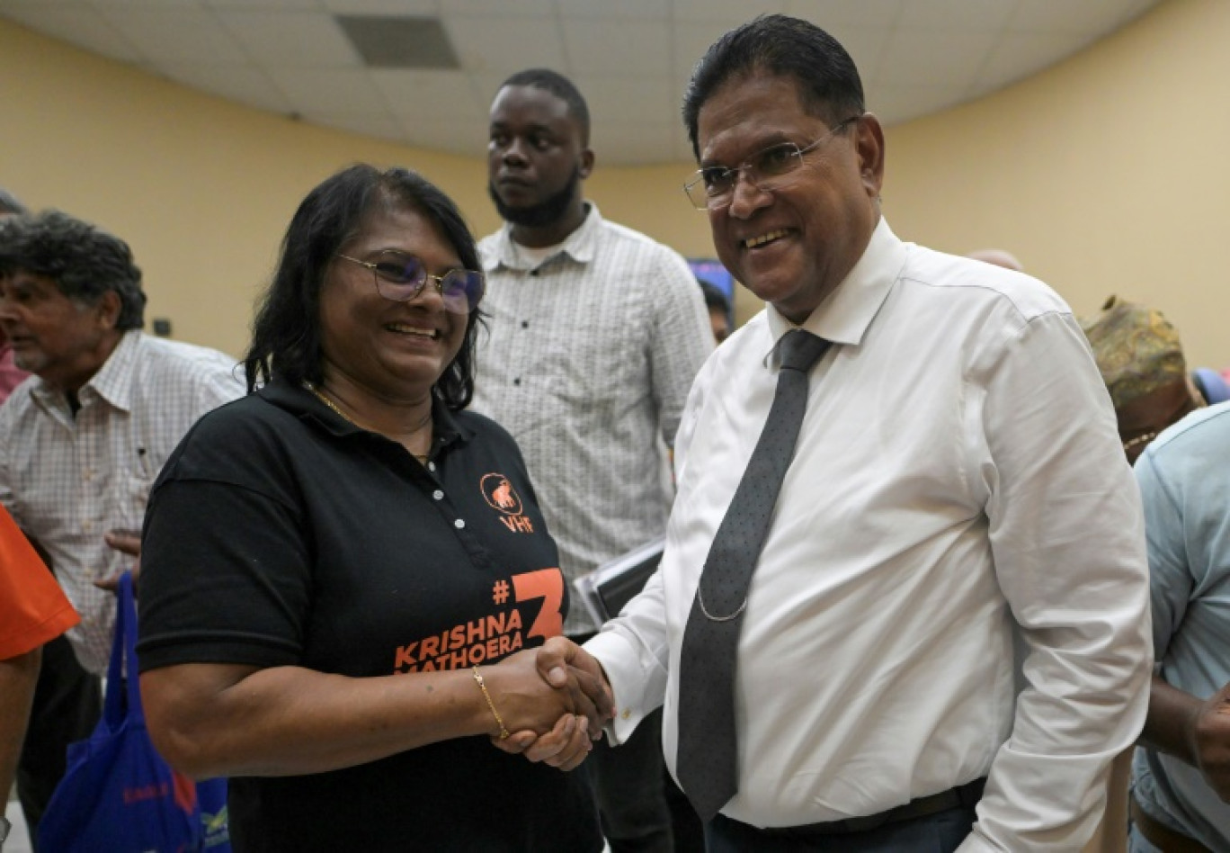 Le président du Suriname, Chandrikapersad Santokhi, serre la main de la ministre de la défense, Krishna Mathoera, après un meeting de campagne de leur parti le VHP à Paramaribo, le 22 mai 2025 © Juan BARRETO