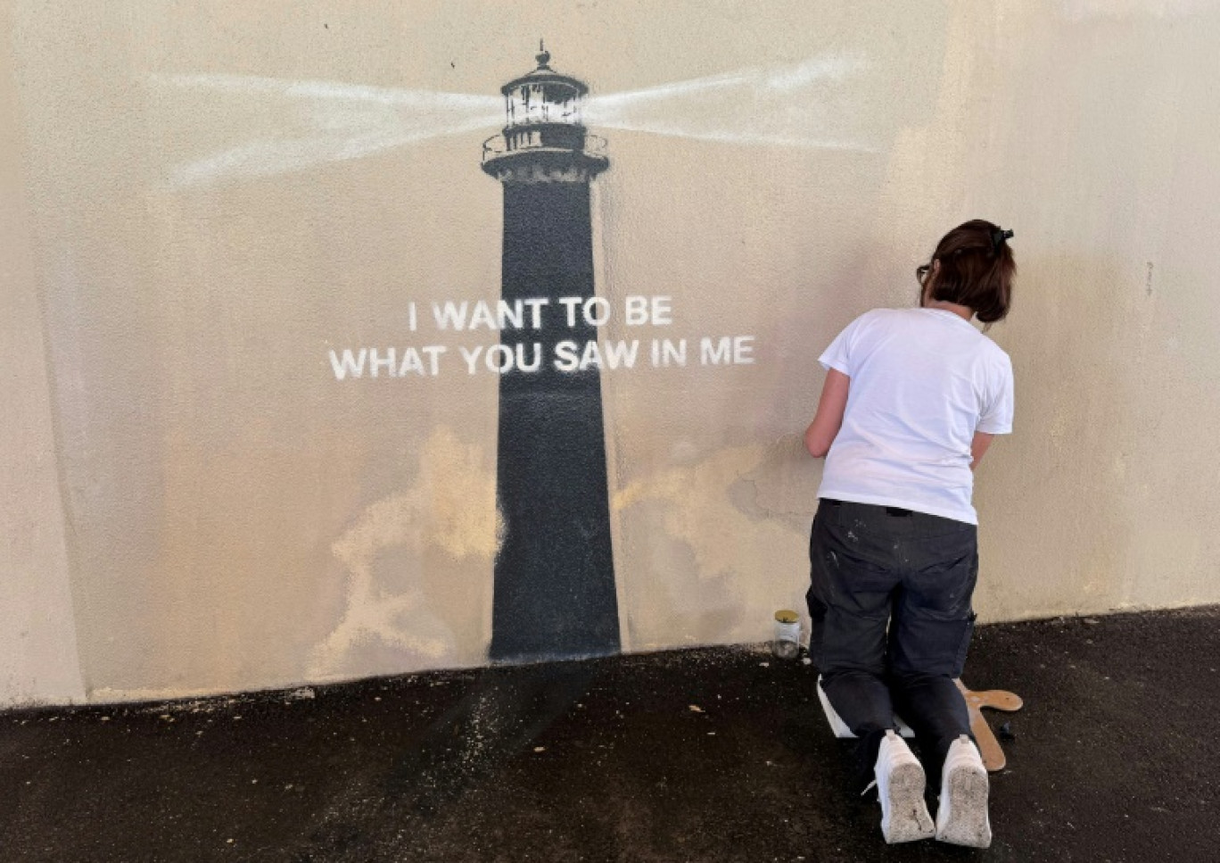 Agnès Perrone, peintre en décor du patrimoine, répare une œuvre d'art de l'artiste de rue Banksy représentant un phare sur la façade d'un bâtiment, après qu'elle a été vandalisée pendant la nuit à Marseille, le 1er juin 2025 © Viken KANTARCI