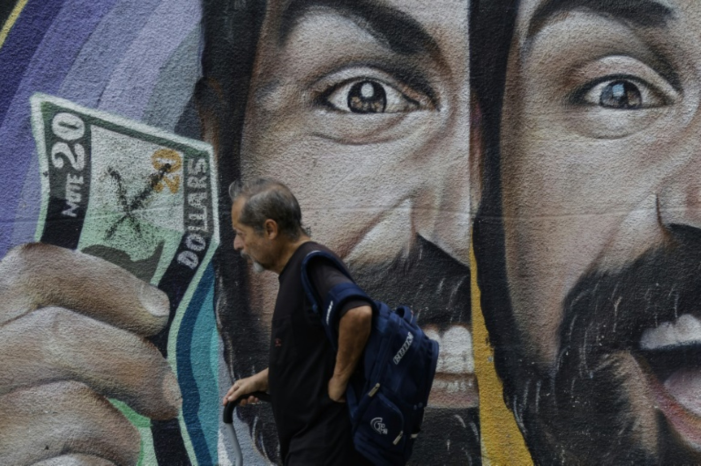 Un habitant passe devant une fresque murale liée aux taux de change à Caracas, au Venezuela, le 2 juin 2025 © Pedro MATTEY