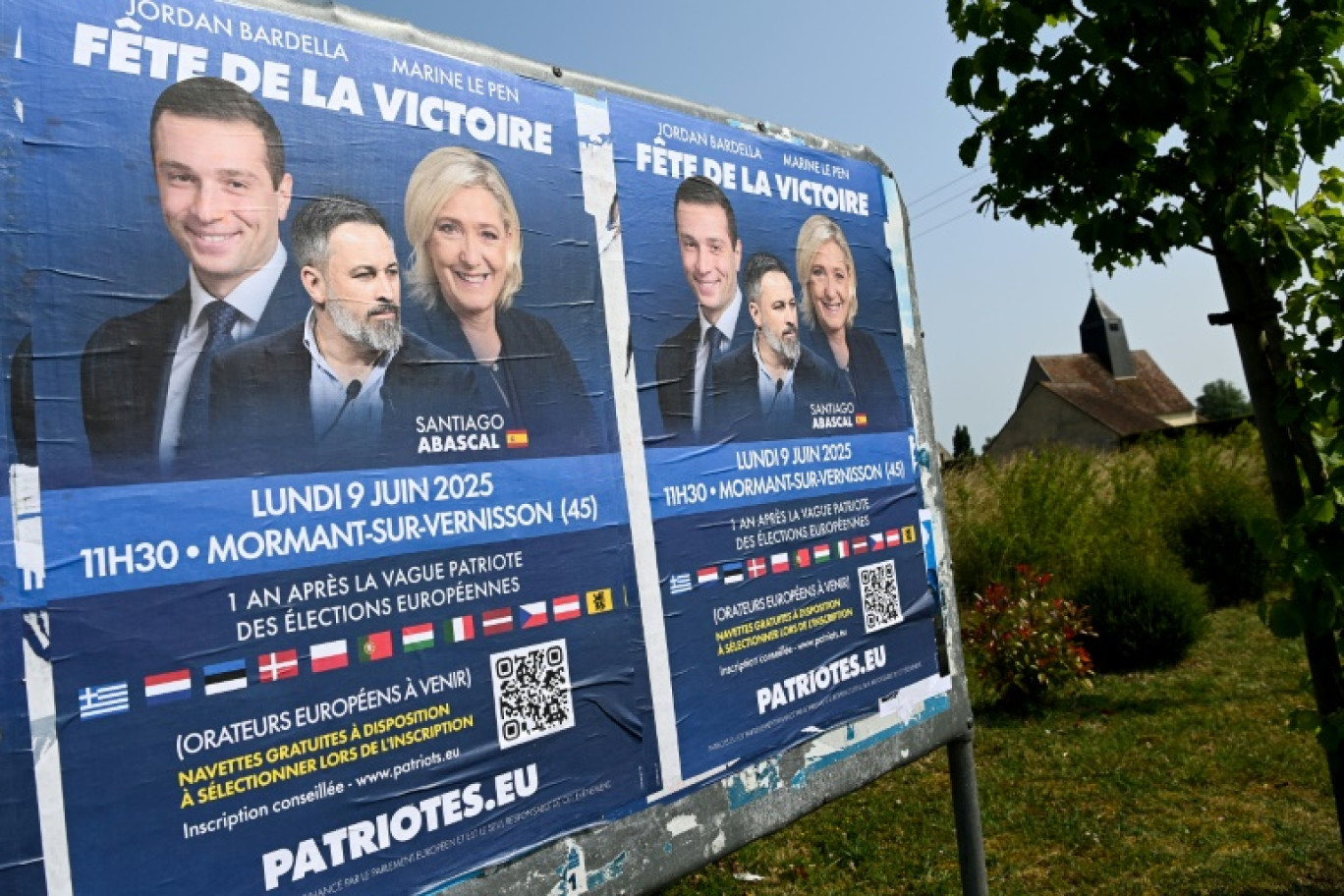 Jordan Bardella (g), président du RN, Santiago Abascal (c), leader du parti espagnol Vox, et Marine Le Pen (d), présidente du groupe RN à l'Assemblée nationale sur des affiches de la "Fête de la victoire", un rassemblement de l'extrême droite européenne organisé par le Rassemblement national (RN) à Mormant-sur-Vernisson, le 9 juin 2025 dans le Loiret © JEAN-FRANCOIS MONIER