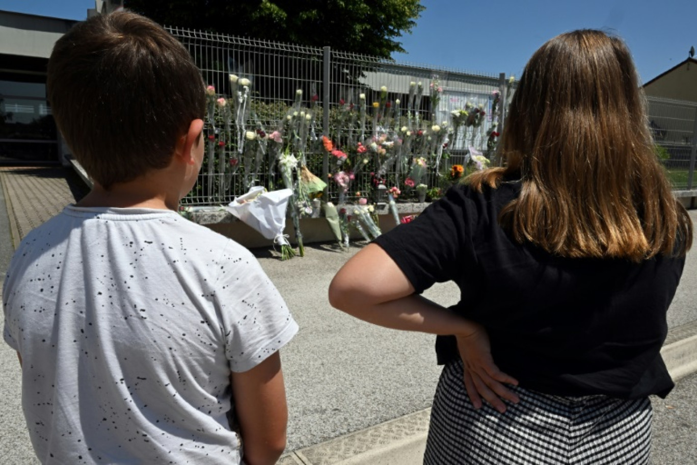 Des élèves regardent des fleurs déposées sur les grilles du collège Françoise-Dolto à Nogent, en Haute-Marne, au lendemain du meurtre d'une surveillante, le 11 juin 2025 © FRANCOIS NASCIMBENI