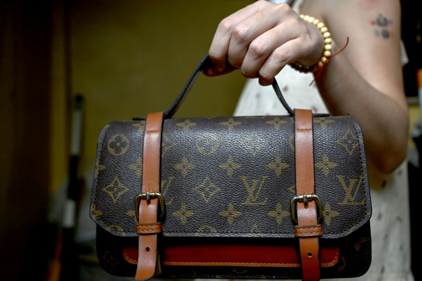 Une femme tient un sac à main Louis Vuitton contrefait, chez elle à Hanoï, le 10 juin 2025 au Vietnam © Nhac NGUYEN