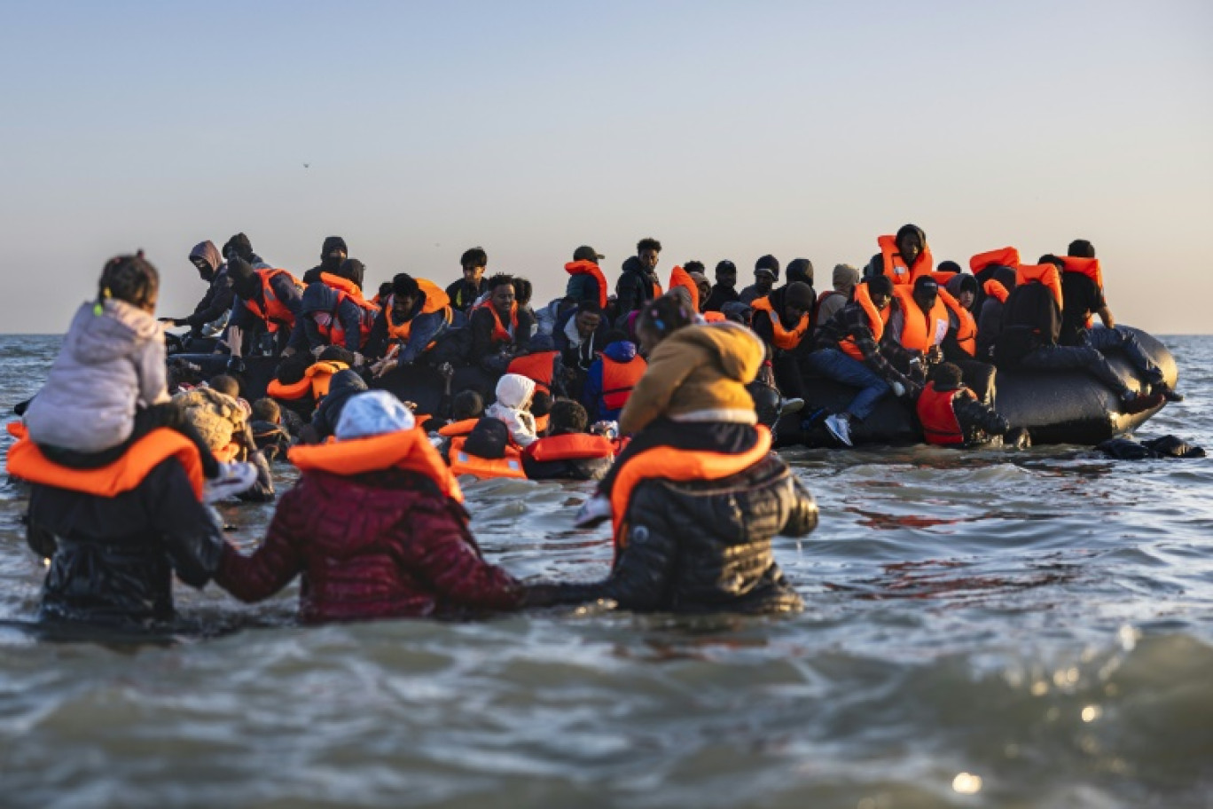 Des migrants avancent dans l'eau pour embarquer sur le bateau d'un passeur et tenter de traverser la Manche au large de la plage de Gravelines, le 16 juin 2025 dans le Nord © Sameer Al-DOUMY