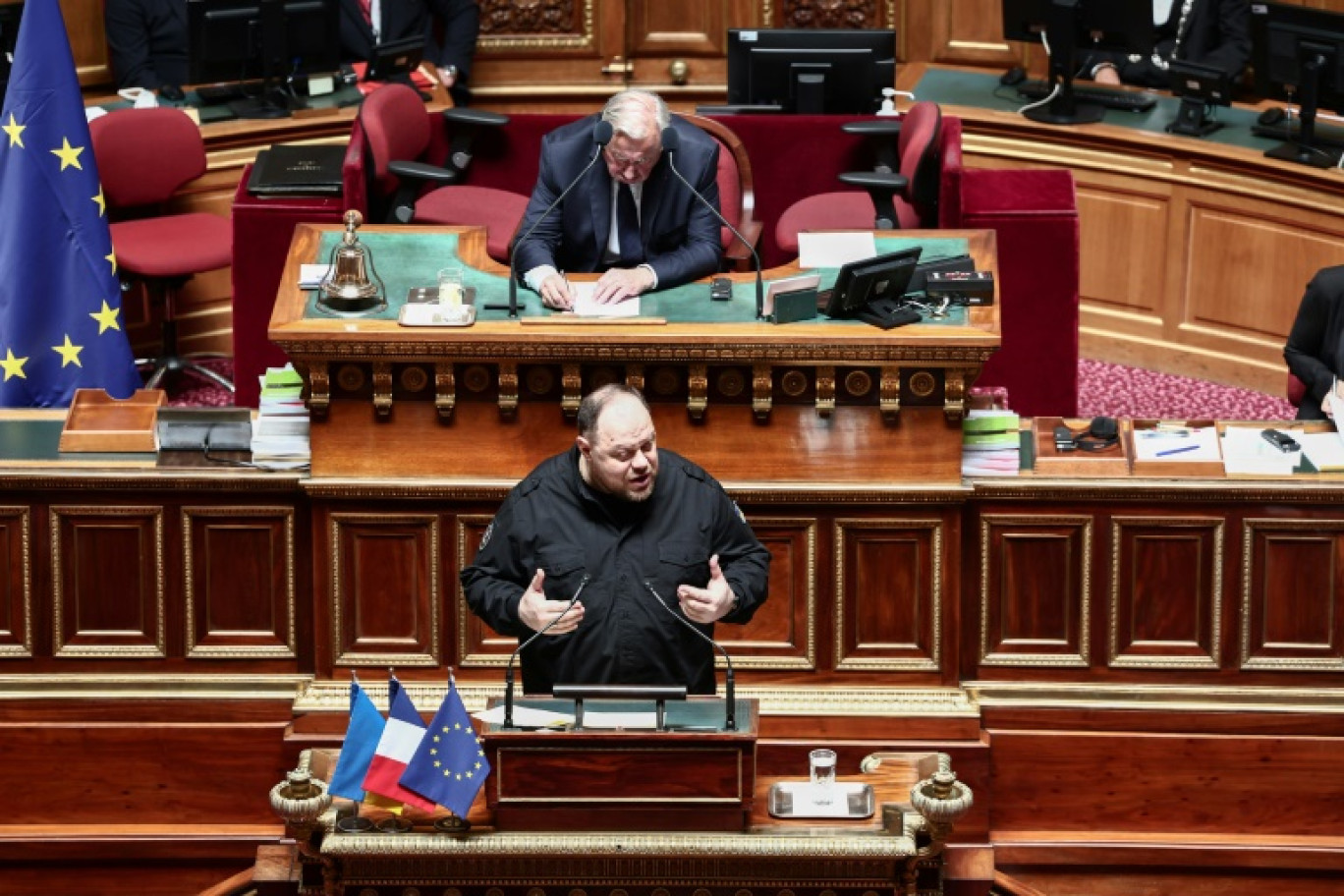 Ruslan Stefanchouk (C) s'exprime devant les sénateurs français, avec en arrière plan le président de la chambre haute Gérard Larcher, à Paris le 18 juin 2025 © Thibaud MORITZ