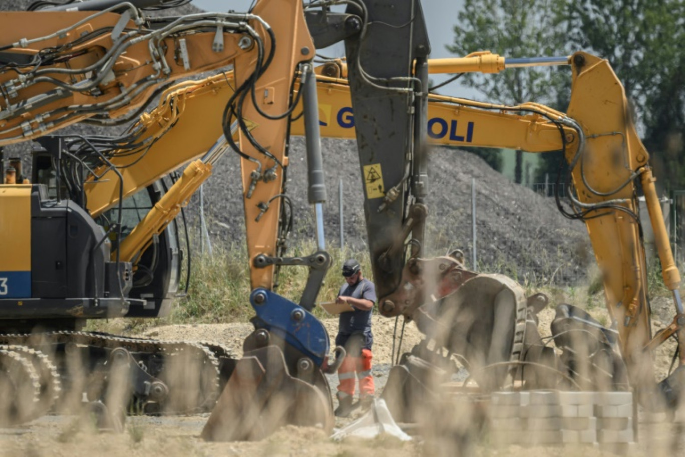 Un ouvrier se tient à côté de pelles mécaniques sur le chantier de l'autoroute A69 près de Verfeil, dans le Tarn-et-Garonne, le 17 juin 2025 © Ed JONES