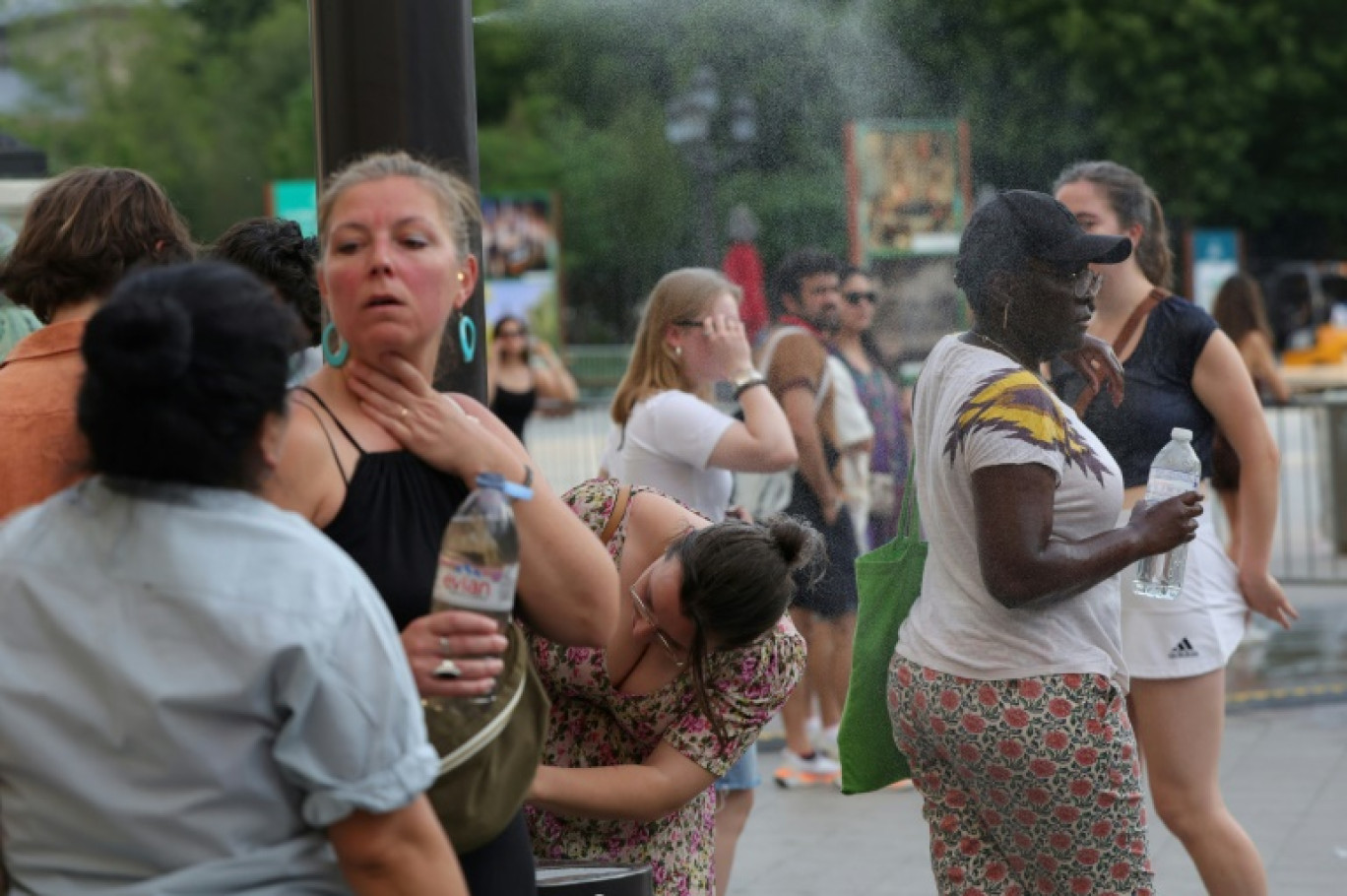 Des personnes se rafraîchissent en traversant un fin brouillard d'eau dans le centre de Paris le 21 juin 2025 © ROMAIN PERROCHEAU
