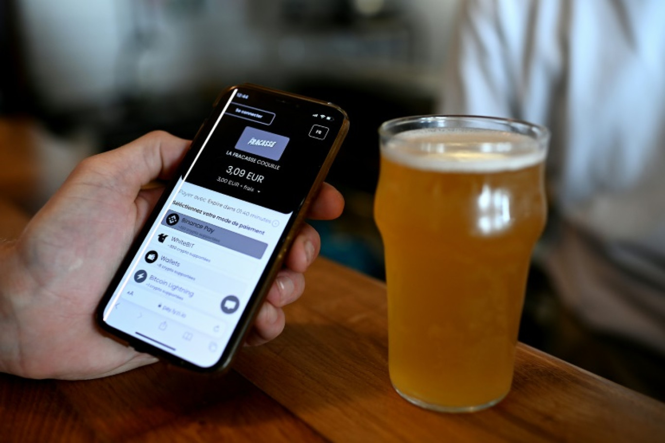 Un paiement en cryptomonnaie via l'application mobile Lyzi au bar La Fracasse à Talence, près de Bordeaux, le 1er juillet 2025 © Christophe ARCHAMBAULT