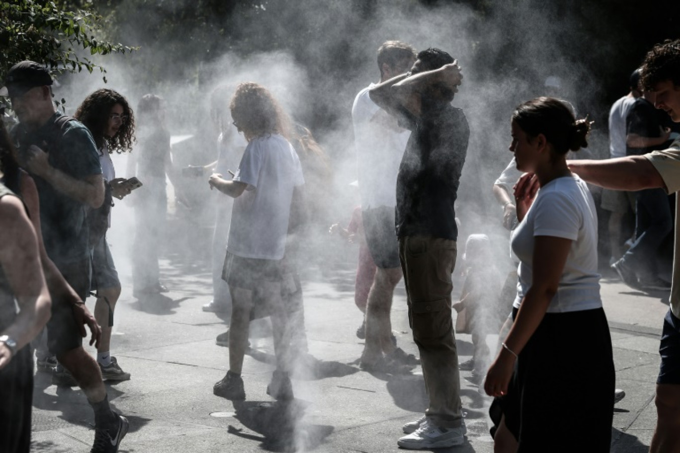 Des passants se protègent du soleil, le 1er juillet 2025 à Paris en période de canicule © Thibaud MORITZ