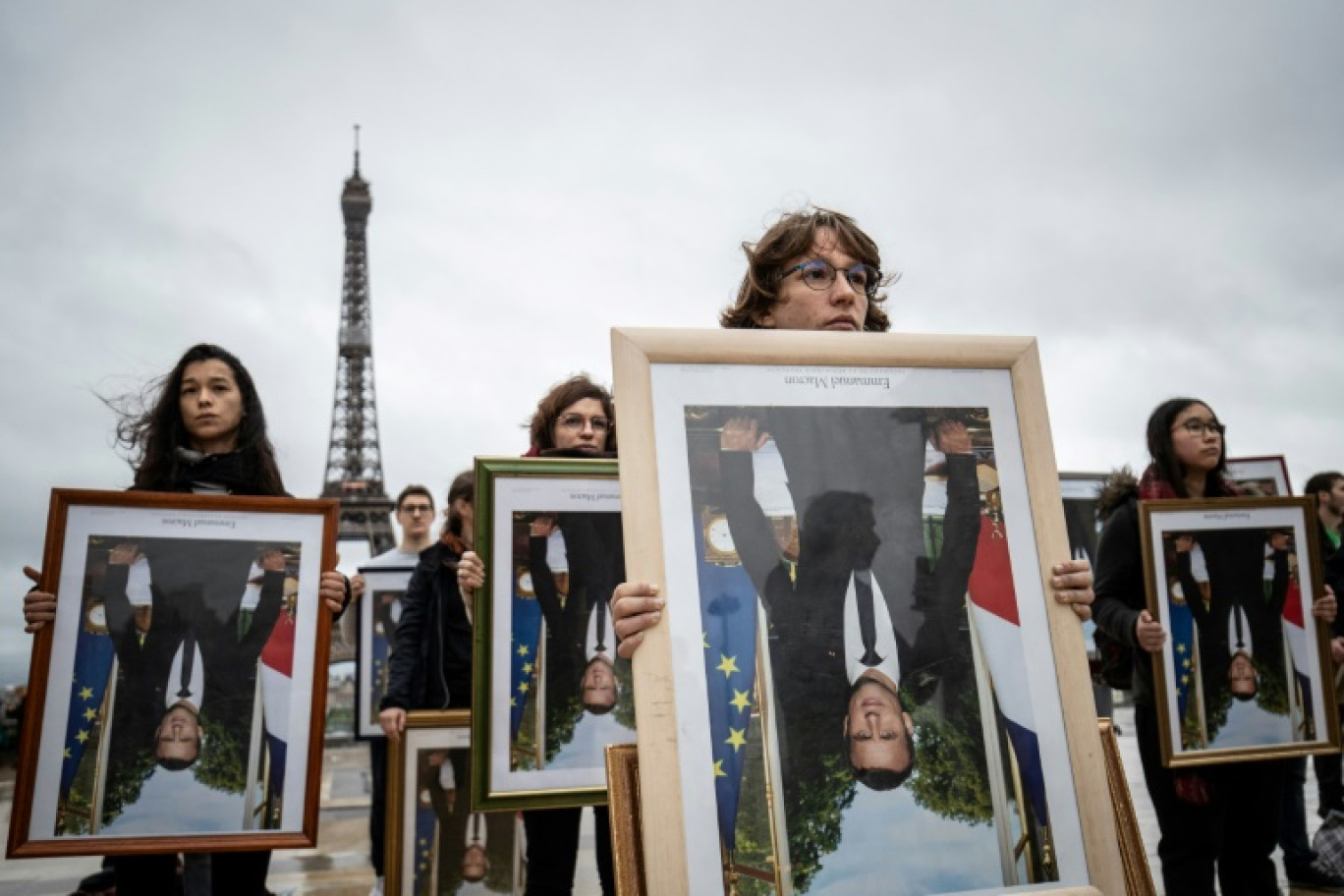 Des militants de l'association Action non violente - Cop21 (ANV-Cop21) tiennent des portraits à l'envers du président Emmanuel Macron décrochés dans différentes mairies, le 8 décembre 2019 sur l'esplanade du Trocadéro, à Paris © Thomas SAMSON