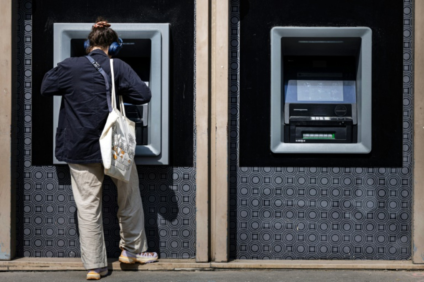 Une femme retire de l'argent à un distributeur automatique bancaire, le 3 juin 2025 à Paris © JOEL SAGET