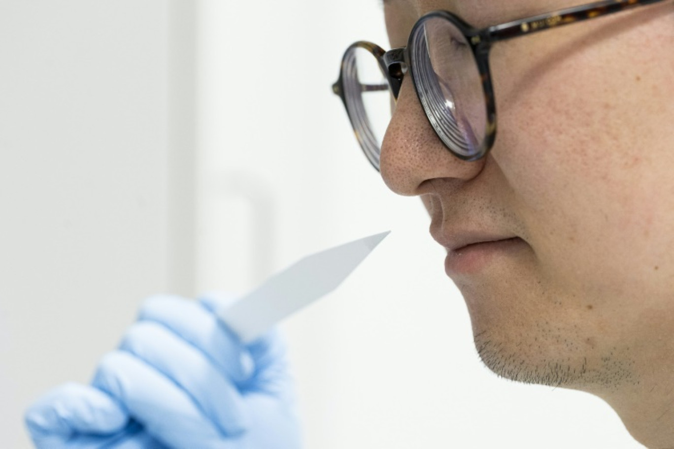 L'élève parfumeur Shangyun Lyu sent une bande odorante utilisée pour évaluer les parfums dans le laboratoire du chimiste allemand Symrise, à Holzminden, le 8 juillet 2025 en Allemagne © MICHAEL MATTHEY