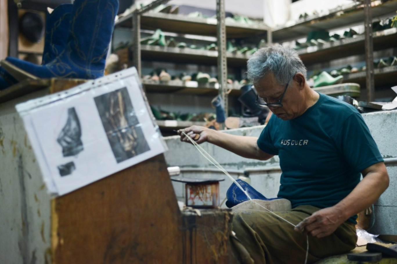 Un ouvrier fabrique une botte qui doit être livrée au marché américain dans l'atelier Tegep Boots, à Bandung (ouest de Java), le 15 juillet 2025 © Timur MATAHARI