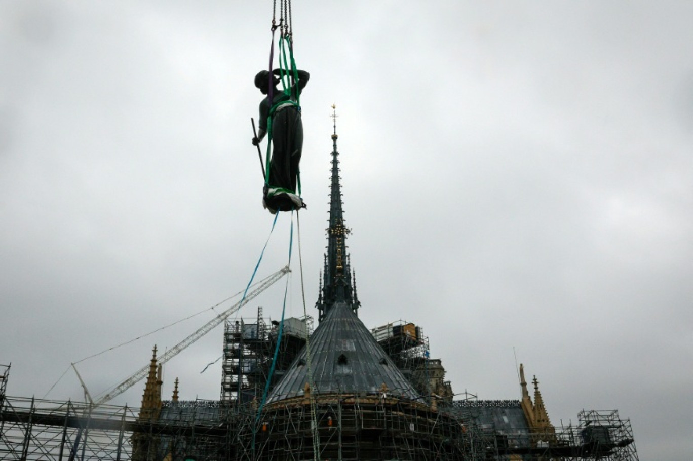 Une grue soulève une statue de Saint-Thomas pour la placer sur la flèche de Notre-Dame de Paris, le 24 juillet 2025 © GEOFFROY VAN DER HASSELT