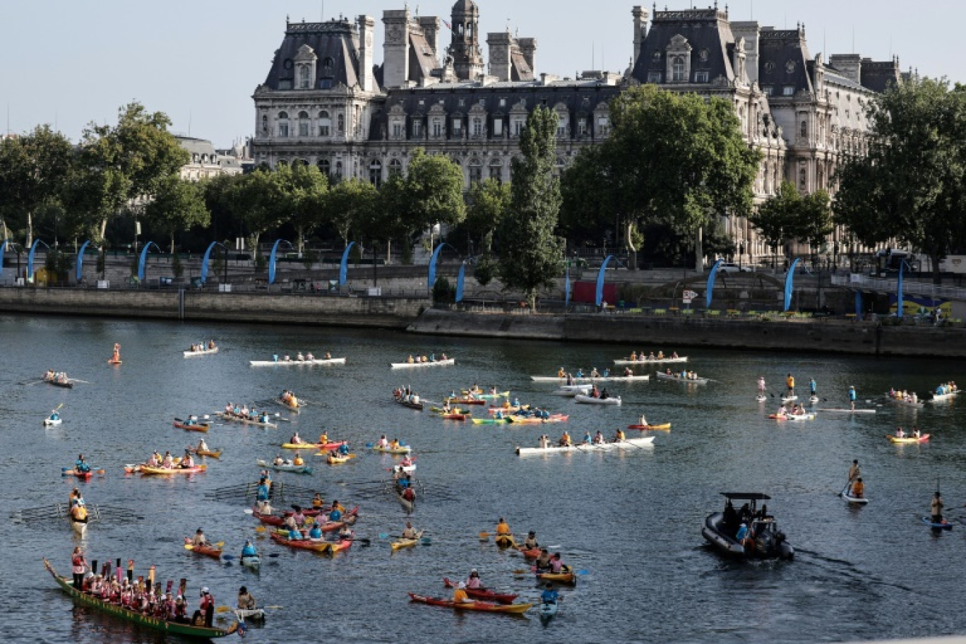 Des kayaks, des paddles et des barques naviguent sur la Seine, avec l'Hôtel de Ville de Paris en arrière-plan, pour marquer le premier anniversaire des Jeux olympiques de Paris 2024, le 26 juillet 2025 © STEPHANE DE SAKUTIN