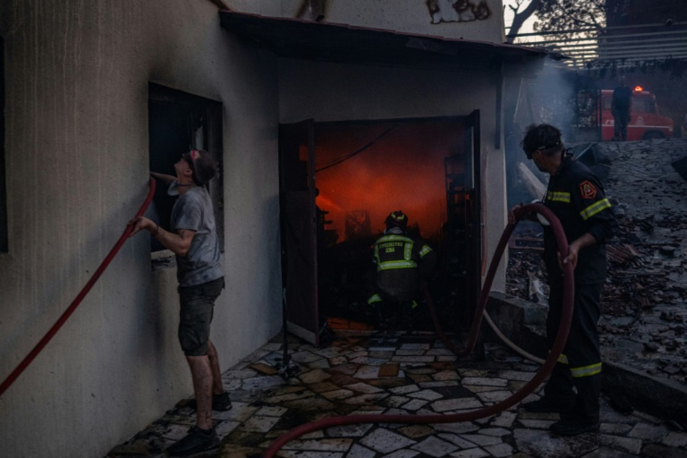 Des habitants et des pompiers luttent contre les flammes à Kryoneri, près d'Athènes, le 26 juillet 2025 © Angelos TZORTZINIS