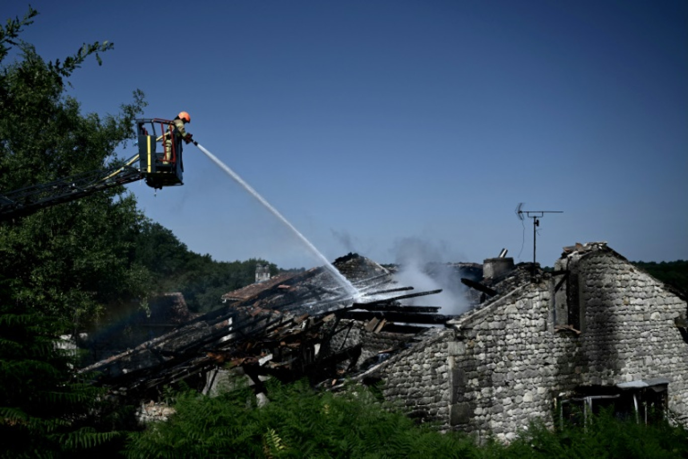 Un pompier s'efforce d'éteindre l'incendie d'un gîte à Montmoreau, en Charente, dans l'ouest de la France, le 28 juillet 2025 © Philippe LOPEZ