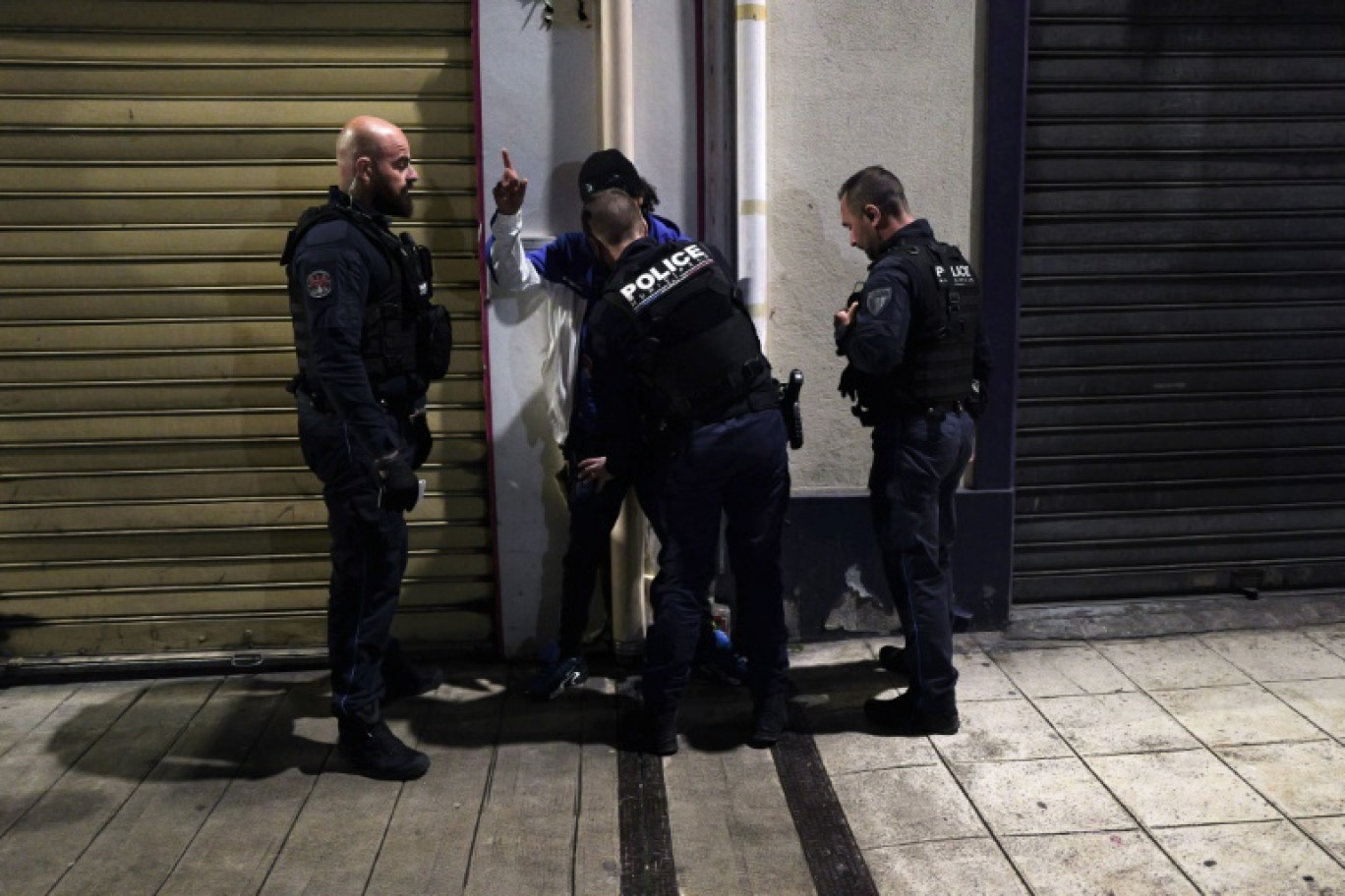 Des policiers municipaux contrôlent un jeune homme dans une rue de Nice alors placée sous couvre-feu nocturne pour les moins de 13 ans, le 2 avril 2024 © Valery HACHE