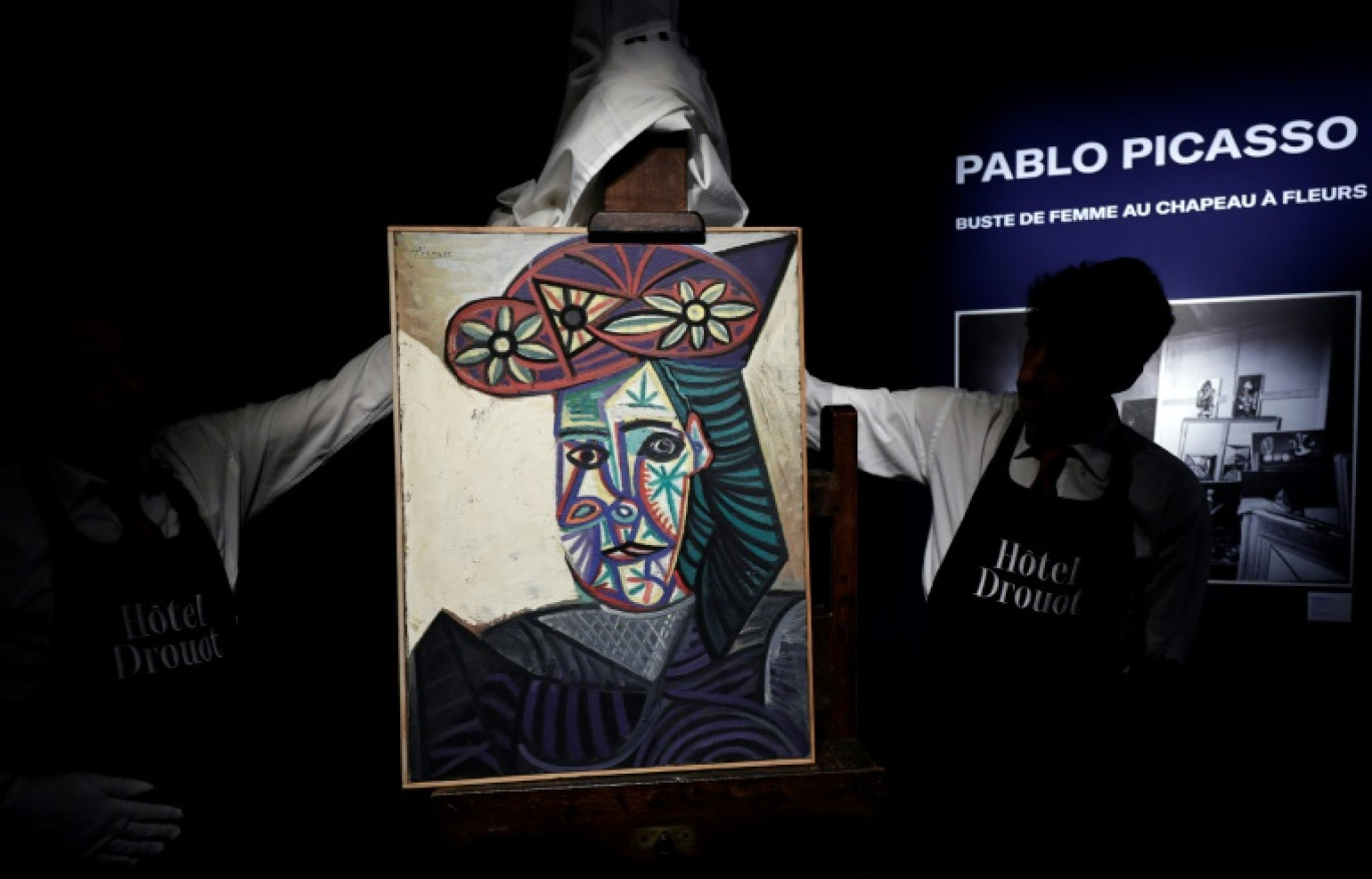 Des employés de l'Hôtel Drouot dévoilent un tableau de Pablo Picasso intitulé "Buste de femme au chapeau à fleurs" représentant Dora Maar, le 18 septembre 2025 à l'Hôtel Drouot à Paris avant la mise aux enchères de l'oeuvre le 24 octobre 2025 © STEPHANE DE SAKUTIN