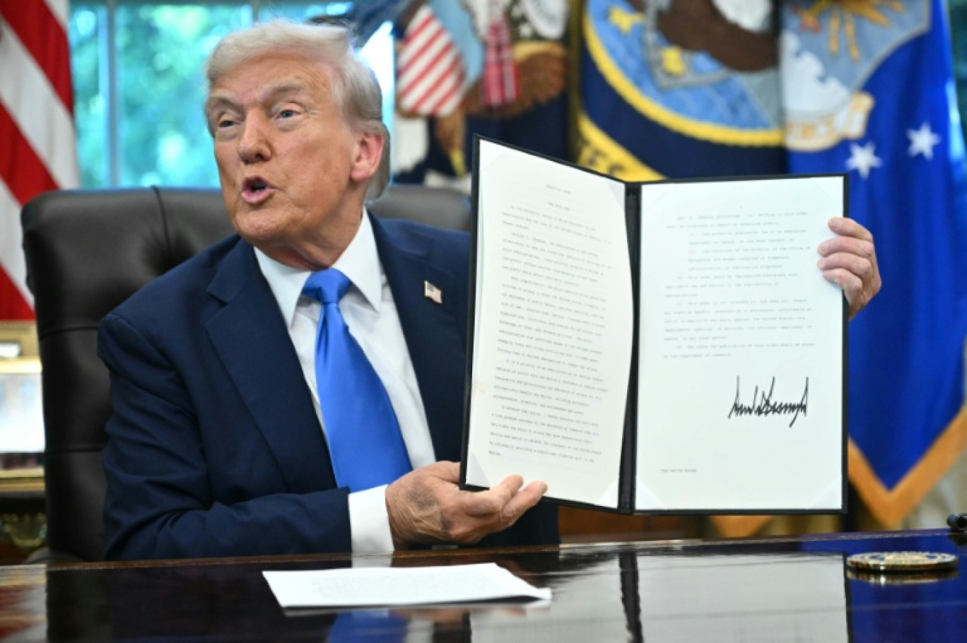 Le président américain Donald Trump présente un décret qu'il vient de signer dans le bureau ovale de la Maison Blanche, à Washington, le 19 septembre 2025 © Mandel NGAN